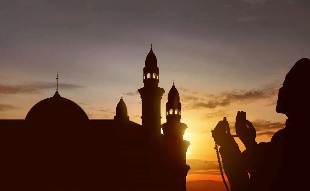 Siluet seorang Muslim berdoa dengan tasbih.